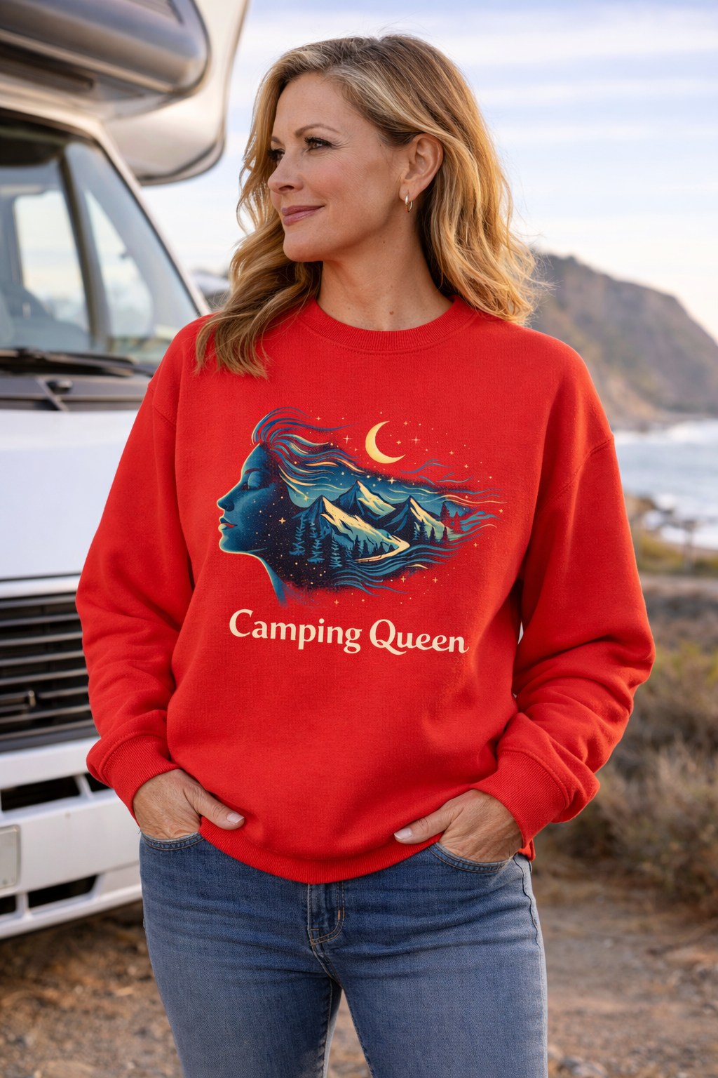 Frau Mitte 50 trägt rotes Camping-Queen Sweatshirt mit ausdrucksstarkem Outdoor-Motiv, steht vor Wohnmobil an der Küste – gemütlicher Camper-Look für Reise & Freizeit.