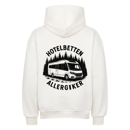 Mann steht vor einem Bergsee und trägt einen orangen Hoodie von Camper4Love mit dem Aufdruck „Hotelbetten Allergiker“ und Van-Motiv – ideal für Outdoor-Fans und Vanlife-Liebhaber.